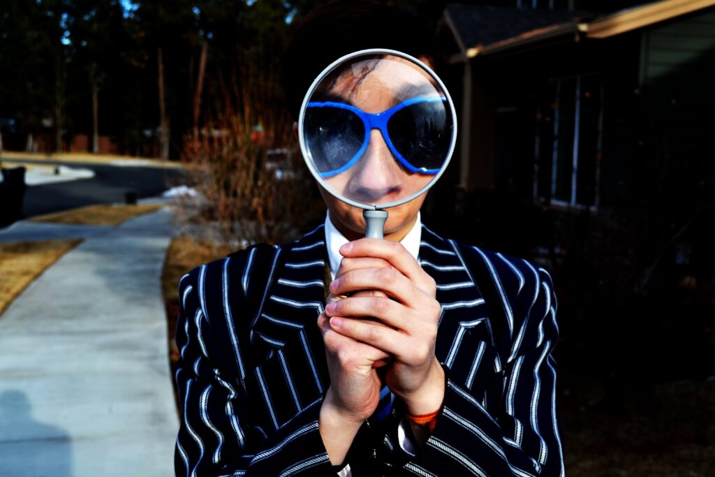 a man in a striped suit with sunglasses on looking through a magnifying glass very close to his face